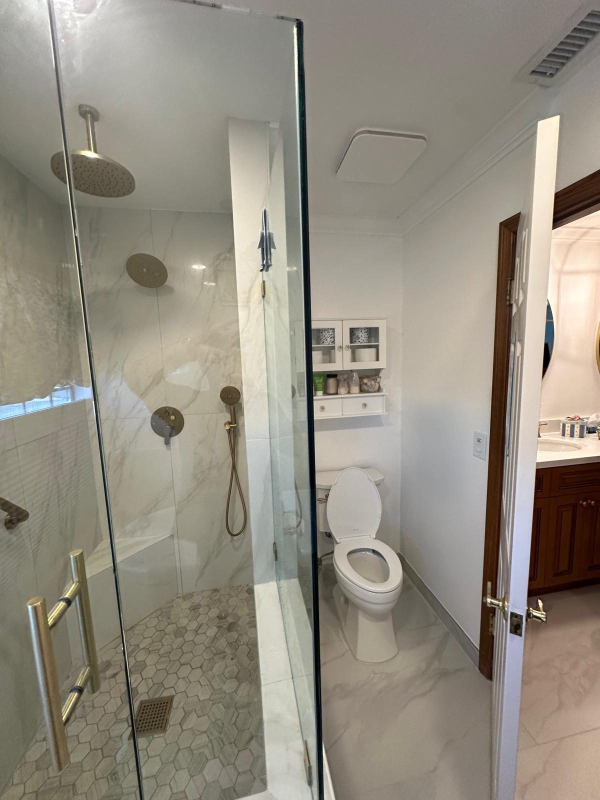 Marble walk-in shower with glass panel and hex floor tile