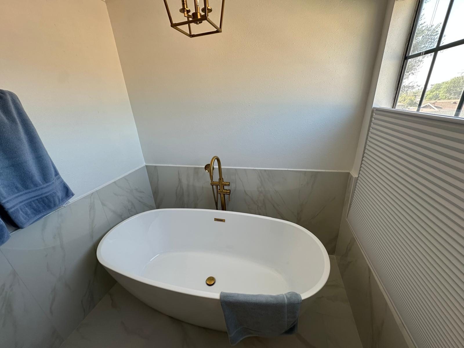 Freestanding soaking tub with marble wainscot and a brass filler